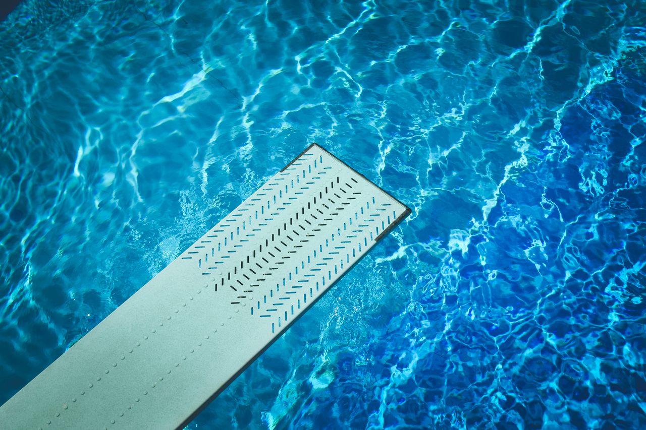Bright blue swimming pool with a diving board on a sunny day